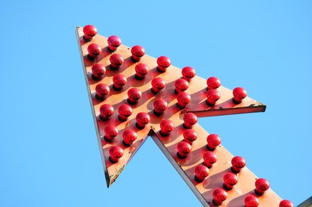 Arrow full of multicolored light lamps decorating an attraction in an amusement park, on a light...
