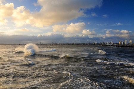 View of the bay of Maldonado, with the buildings on the horizon, under a cloudy sky and a rough seaの写真素材
