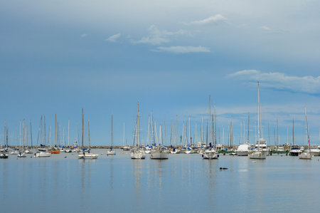 Stormy afternoon with a dark sky, and many sailboats moored in the Puertito del Buceo harbourの写真素材