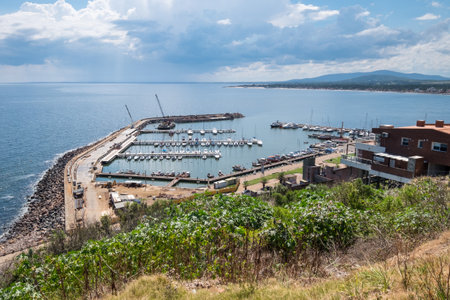 A beautiful view of the ocean with a few boats docked at the pier. The sky is cloudy, but the water is still calmの写真素材