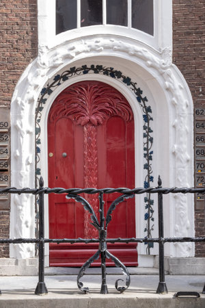 A red door with a black iron gate in front of it. The gate is decorated with vinesの写真素材