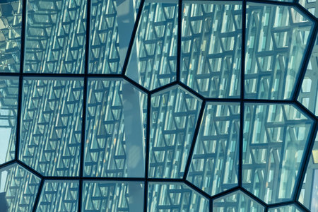 Modern glass facade with geometric patterns reflecting sunlightの写真素材