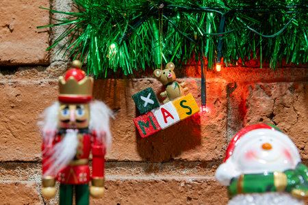 Festive Christmas decor: nutcracker, snowman, 'XMAS' sign, brick wall background