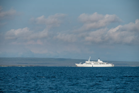 A white cruise ship sails across the vast ocean under a cloudy blue sky.の写真素材