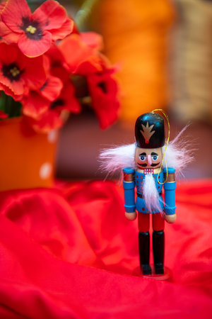 Nutcracker soldier with white beard, red fabric, and vibrant flowers backgroundの写真素材