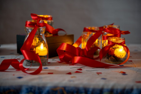 Candlelight in glass jars with red ribbons, creating a cozy festive atmosphereの写真素材