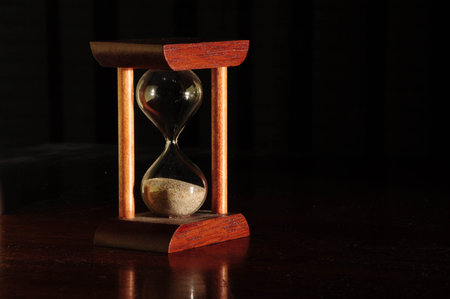 Hourglass with wooden frame on dark background symbolizing time passage