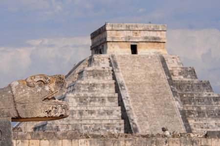 Chichen Itza ancient ruins with pyramid and carved serpent under blue skyの写真素材