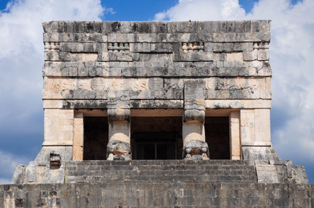 Chichen Itza's ancient stone structure with bright blue sky and fluffy cloudsの写真素材