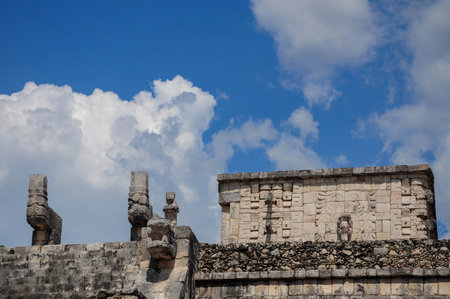 Ancient stone structures of Chichen Itza under a vibrant sky with cloudsの写真素材