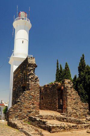 Historic lighthouse over ancient stone ruins in Colonia, Uruguay.の写真素材
