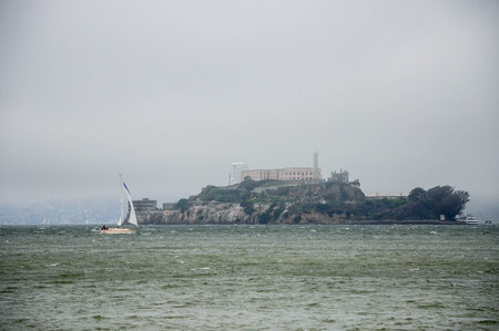 Foggy Alcatraz Island with Sailboat on Choppy San Francisco Bay Watersの写真素材