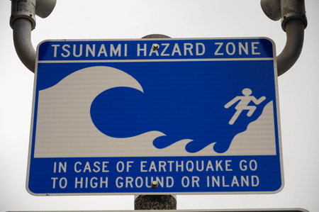 Blue tsunami hazard sign advising evacuation to high ground during earthquakesの写真素材