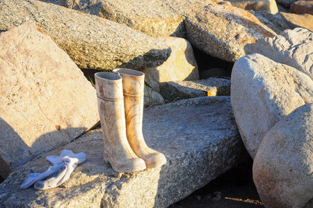 Worn-out boots and socks on boulders in warm afternoon sunlightの写真素材