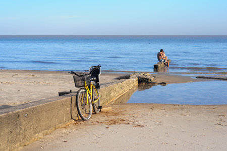 Cyclist resting by serene seaside, enjoying morning beach scenery