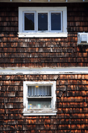 Weathered rustic wooden exterior with two windows and white framesの写真素材