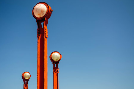 Red lampposts contrast against clear blue sky.の写真素材