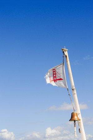 Flag with red bridge symbol on white mast against clear blue sky