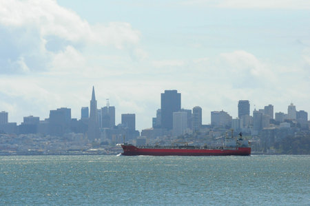 Red cargo ship in San Francisco Bay with city skyline in backgroundの写真素材