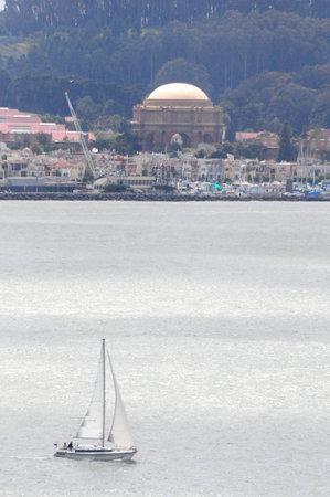 Sailboat in San Francisco Bay near Palace of Fine Arts and lush treesの写真素材