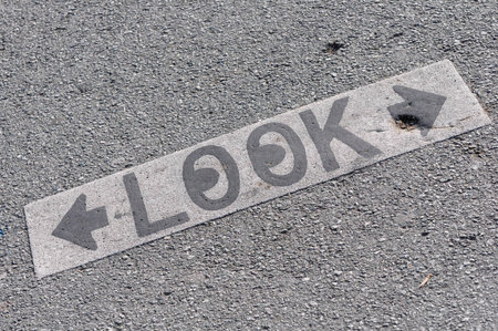 Pedestrian safety: 'LOOK' sign with arrows on textured asphalt.の写真素材