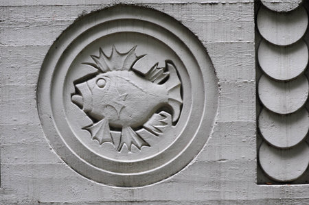 Intricate concrete fish relief on wall, showcasing detailed geometric designの写真素材