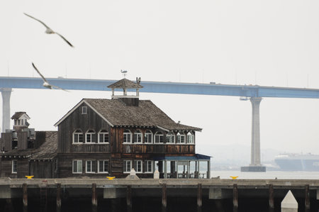 Wooden house by San Diego Bay with seagulls and bridge in background.の写真素材