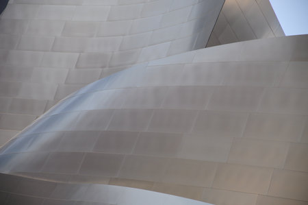 Modern architecture with curving metallic surfaces reflecting sunlightの写真素材