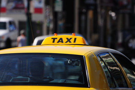 Yellow taxi navigates bustling urban streets, symbolizing city life.の写真素材