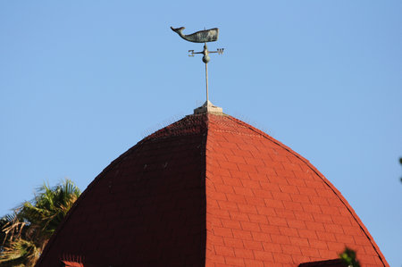 Red dome with whale vane under clear sky at historic seaside hotelの写真素材