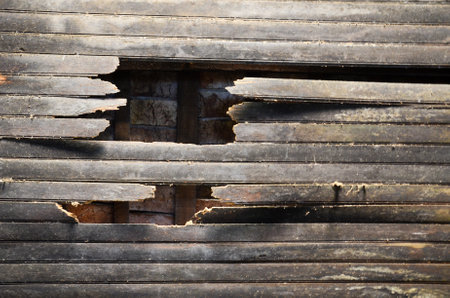 Close-up of weathered wood planks with a hole against brick wall backdropの写真素材