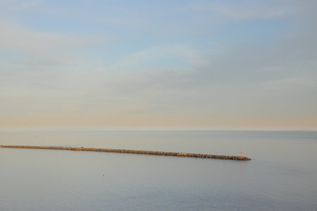 Tranquil seascape: stone jetty, calm waters, pastel sunset skyの写真素材