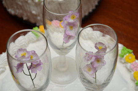 Glass goblets with purple flowers on a white decorative surfaceの写真素材