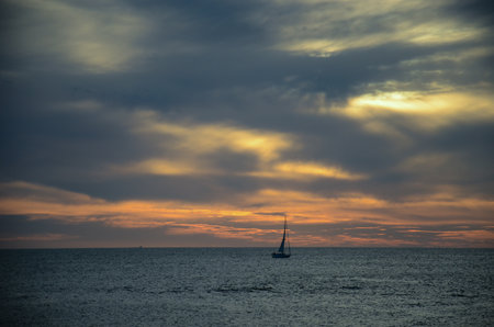 Sunset over Punta del Este bay with silhouette of lone sailboat.の写真素材