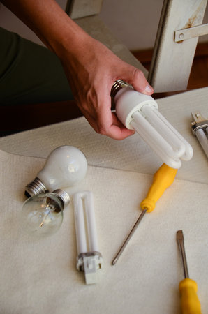 Person exploring energy-efficient lighting with bulbs and tools on tableの写真素材