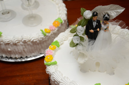 Elegant wedding cake with floral decor and couple topper on wooden tableの写真素材