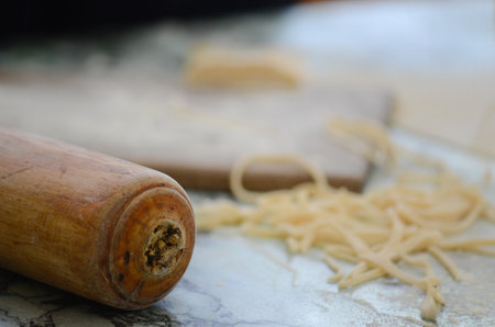 Fresh Pasta with Rustic Rolling Pin on Marble Surfaceの写真素材