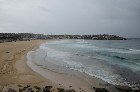 Overcast beach day with waves and cityscape in Sydney, Australiaの写真素材