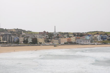 Calm beach with bustling cityscape and vibrant buildings in the backgroundの写真素材