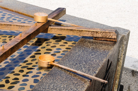Japanese purification fountain with wooden ladles at shrine in bright sun