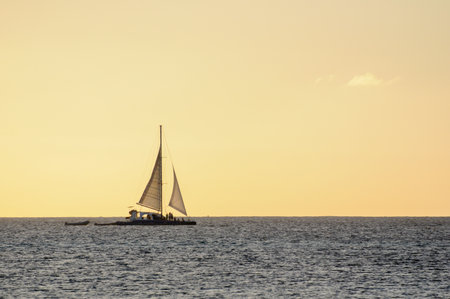 Sailboat drifting on calm ocean at sunset, serene and tranquil moodの写真素材