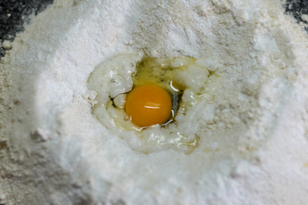 Cracked egg in flour, ready for dough mixing close-upの写真素材