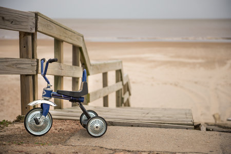 Tricycle by boardwalk to serene sandy beachの写真素材