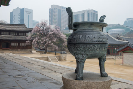 Bronze urn at Deoksugung Palace with Seoul skyline in backgroundの写真素材