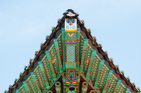 Ornate Korean temple roof with patterns against clear blue sky