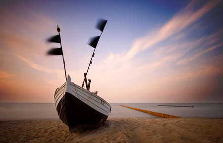fishing boat on the beach to the baltic sea in the evening lightの写真素材