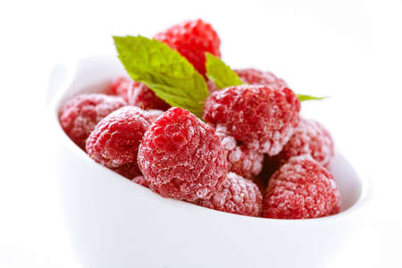 Bowl of refreshing frozen raspberries covered in frosting for a delicious healthy dessert, tilted closeup angleの写真素材
