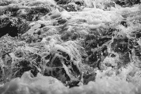Close-up view of the sea waves and foam. Black and white photo.