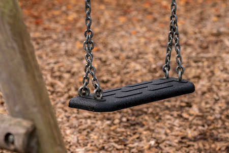 Empty swing hanging on a chain in a playground. Selective focus.の写真素材