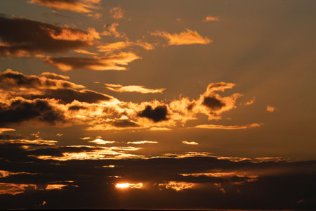 beautiful sunset at the sea with orange clouds and sunbeamsの写真素材